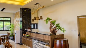 A modern kitchen with a marble island, wooden cabinets, and a unique tree-shaped light fixture. - Hola sea view B&B (Shoufeng)