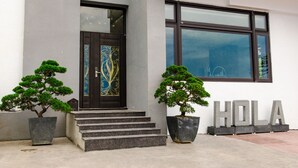 A building entrance with a dark door, steps, and two potted trees. - Hola sea view B&B (Shoufeng)