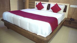 A large bed with a wooden frame and white bedding, including a red throw blanket and pillows. - Sky Stays Heaven (Dwarka)