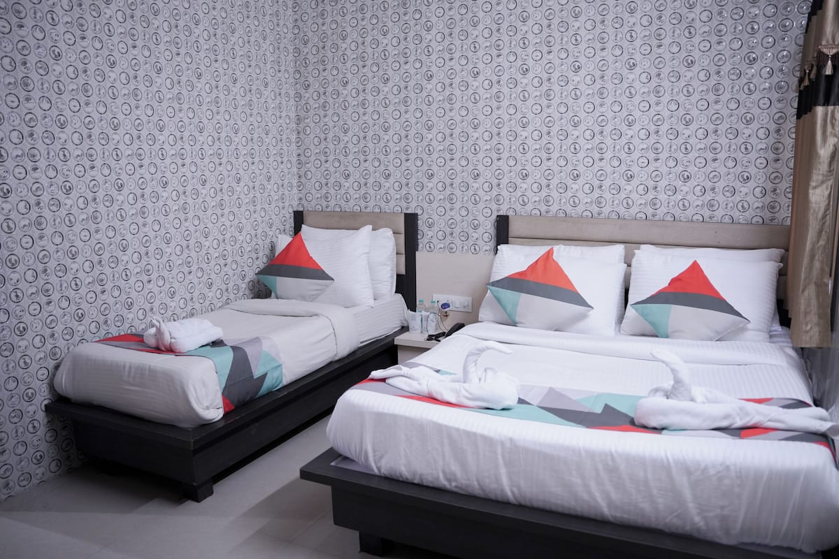 Une chambre d’hôtel avec deux lits, chacun doté de draps blancs et d’oreillers à motifs géométriques.