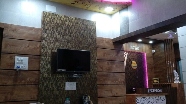 A reception area with a modern design, including a flat-screen TV, a reception desk, and a ceiling with a circular light fixture. - Sky Stays Heaven (Dwarka)