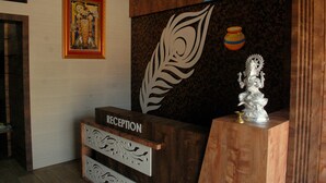 A reception desk with a wooden finish, a framed religious painting, and a decorative wall piece. - Sky Stays Heaven (Dwarka)