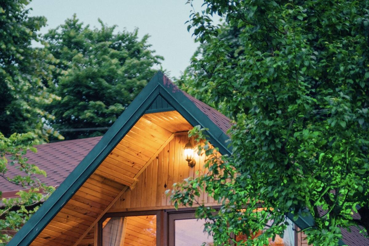 Une cabane en bois avec un toit en pente, un escalier menant à une porte et un banc au premier plan.