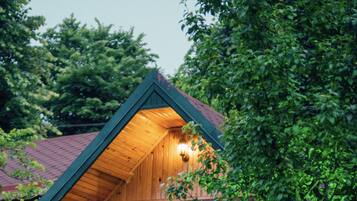 A wooden cabin with a sloped roof, a staircase leading to a door, and a bench in the foreground.