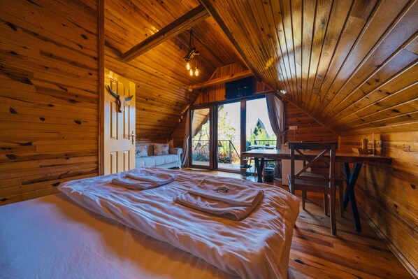 Une chambre confortable dans un chalet en bois, avec un grand lit, une table à manger et une vue par la fenêtre.