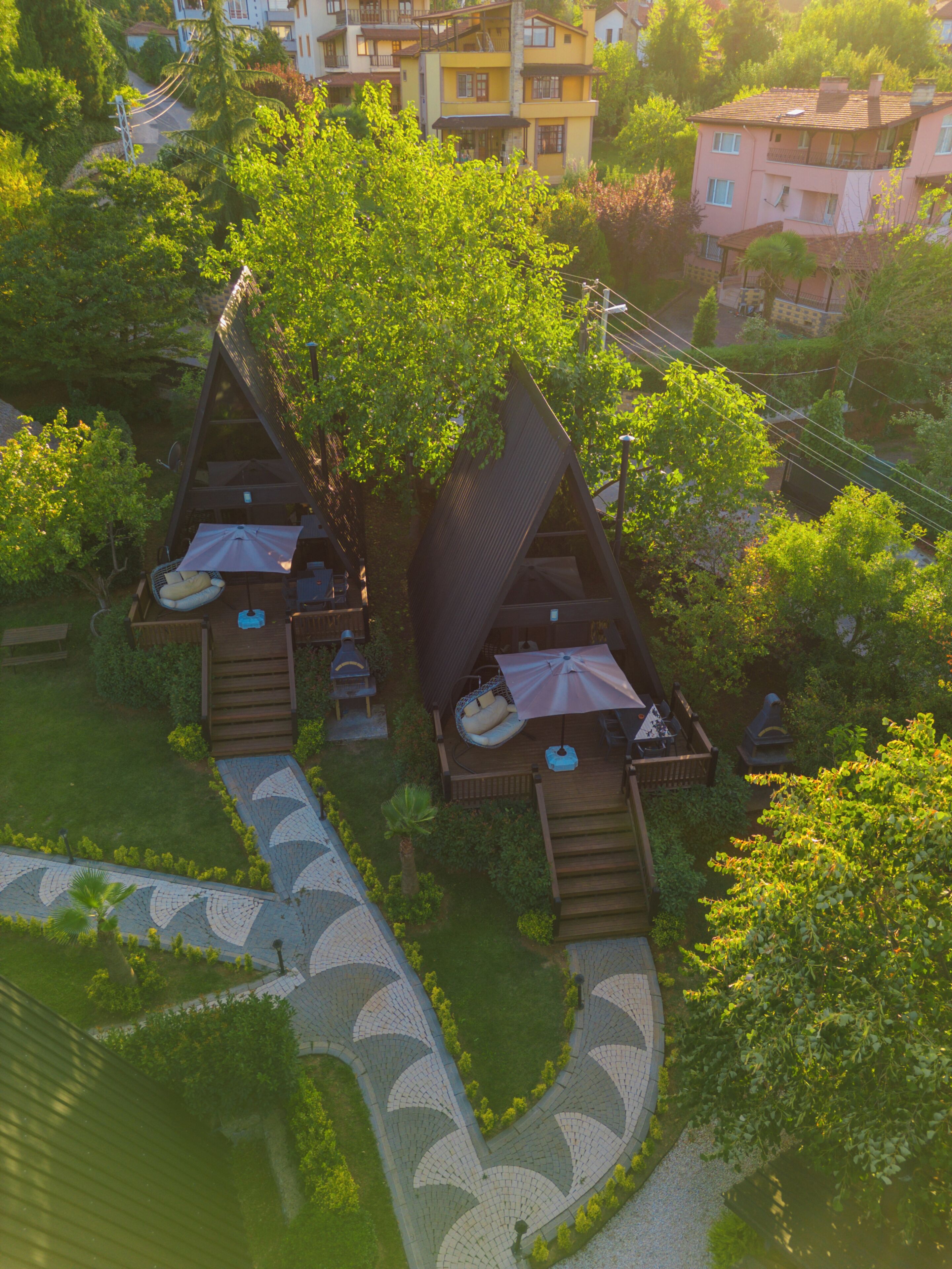 A residential area with two treehouse-like structures with outdoor seating and a paved pathway.