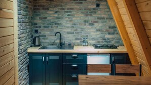 Una cocina compacta con pared de ladrillo, vigas de madera en el techo y un lavamanos empotrado.