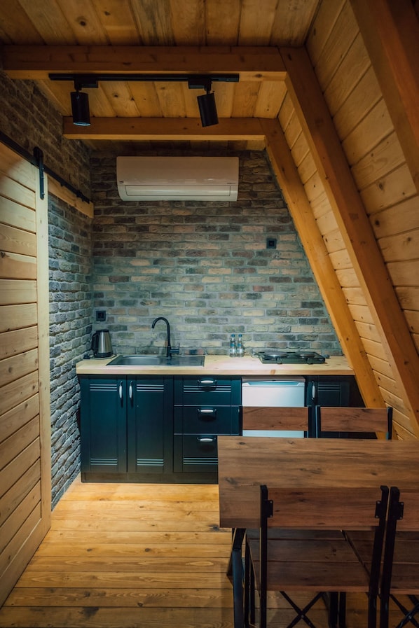 Une cuisine de taille réduite avec un mur en briques, des poutres en bois au plafond et un évier encastré.