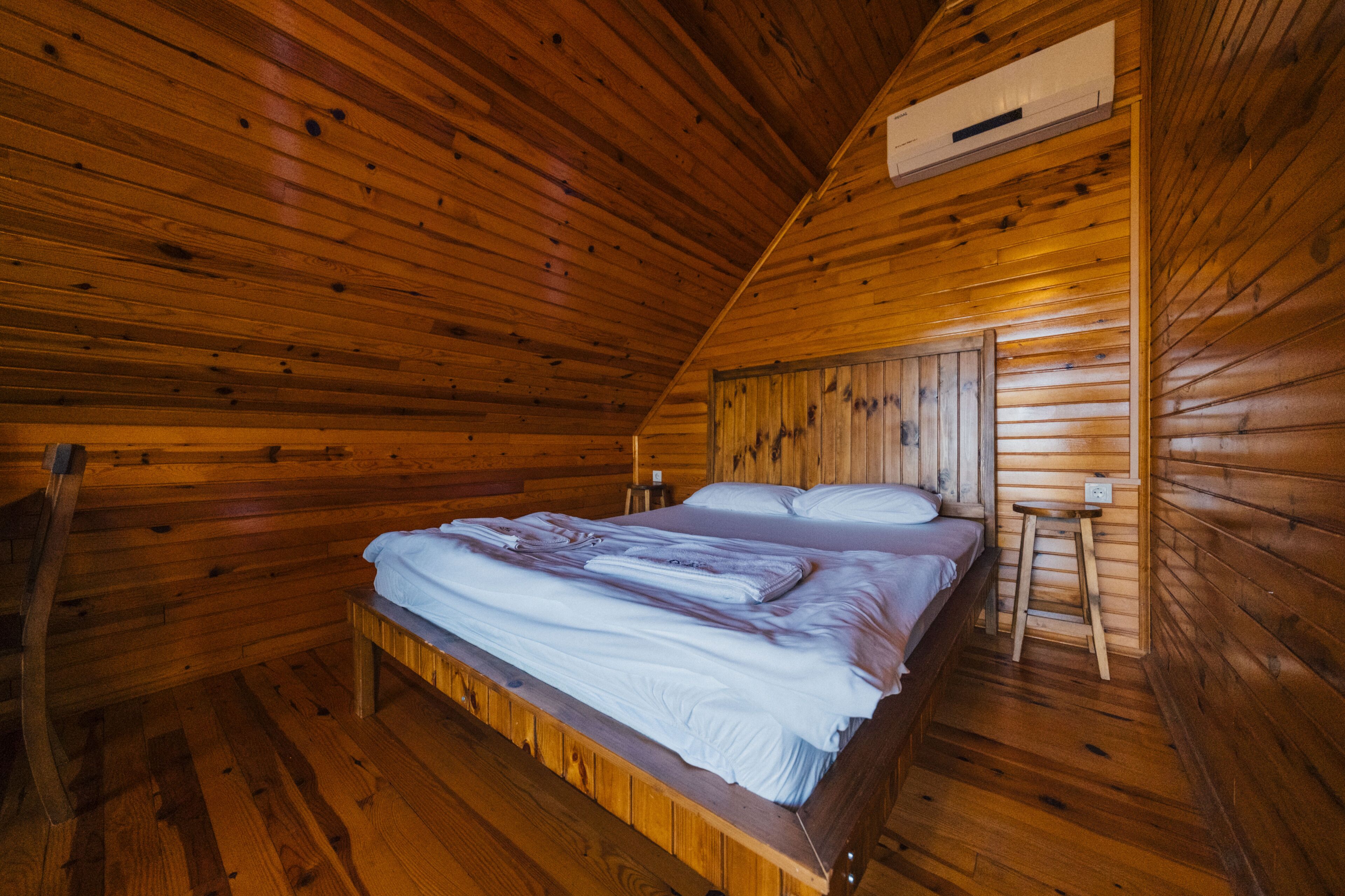 Camera da letto in una baita di legno con un letto, un comodino e una scala.