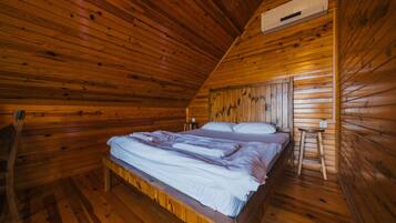 A wooden cabin bedroom with a bed, a nightstand, and a ladder.