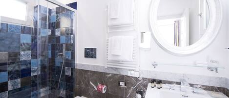 Un baño moderno con cabina de ducha de vidrio, inodoro, lavabo con espejo y toallero.