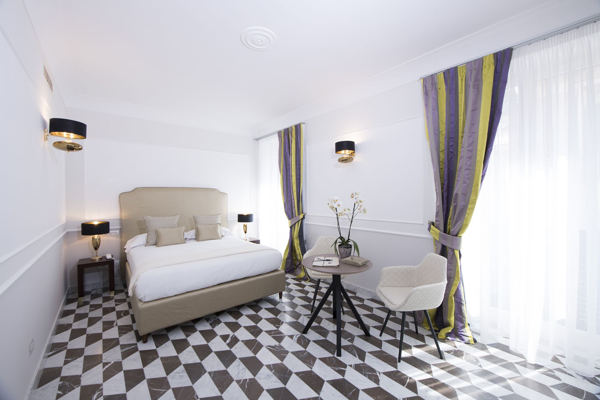 A hotel room with a large bed, a small round table with a chair, and a check-in counter.