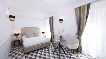 Quarto de hotel com uma cama grande, uma mesa redonda pequena e uma cadeira, e um balcão de recepção.