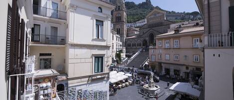 A bustling street scene with a variety of shops and outdoor seating areas, suggesting a lively urban atmosphere.