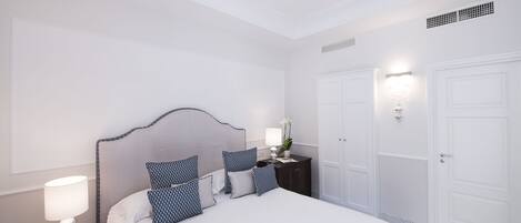 Habitación de hotel con cama, mesitas de noche, lámpara y una luz en la pared.