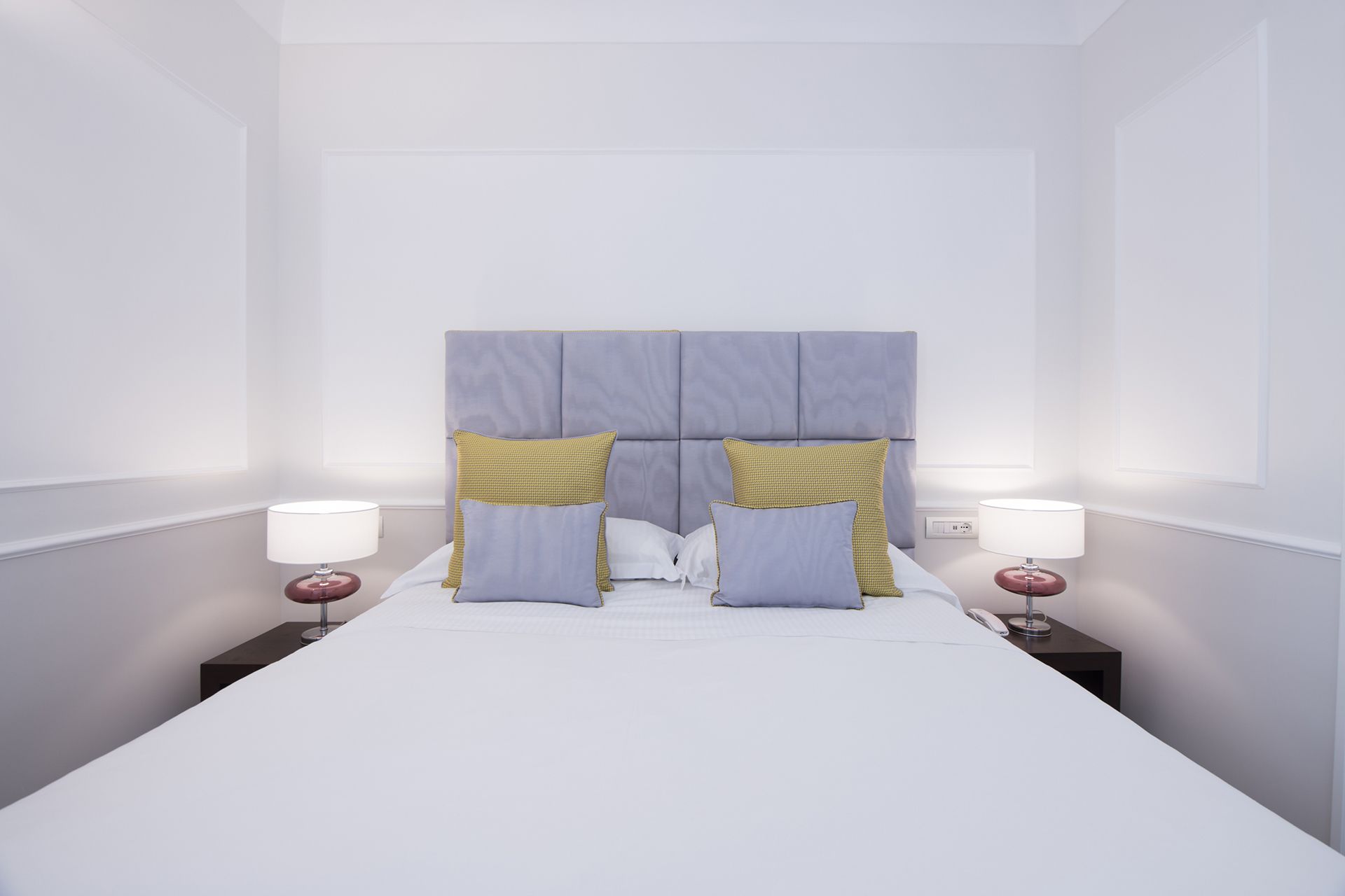 A hotel room with a large bed, two bedside tables, and a headboard.
