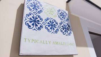 A sign with blue and green decorative patterns and the text "TYPICALLY AMALFITANO" on a white background.
