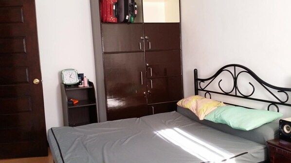 A bedroom with a bed, a wardrobe, a shelf with items, and a door. - Ramyer Transient House 1 - Tagbilaran (Tagbilaran)