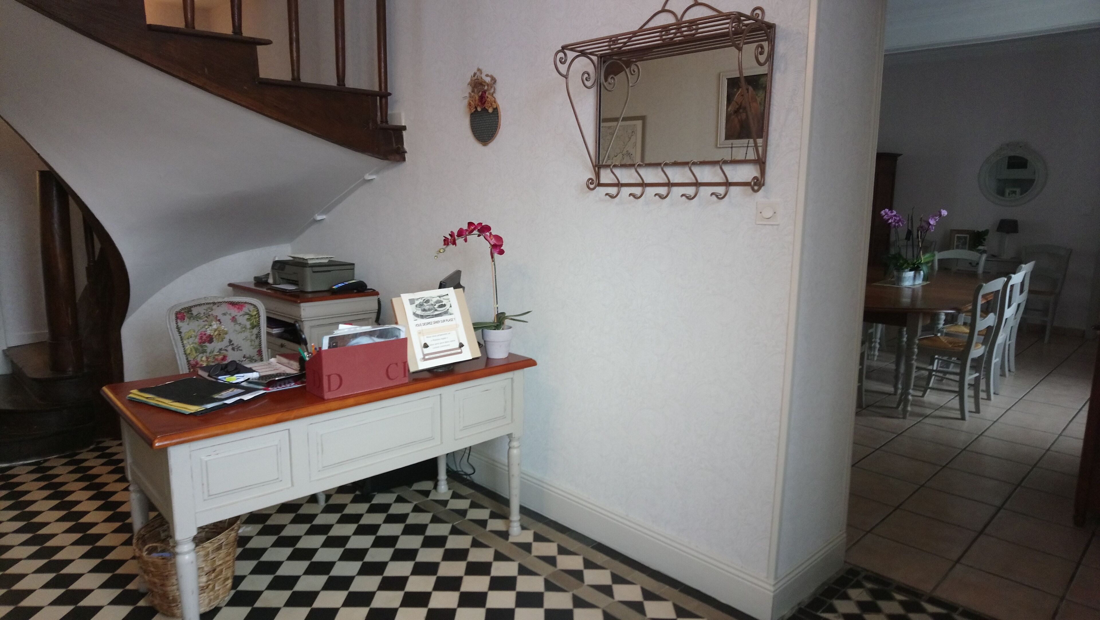 Un sol à carreaux, un bureau avec une imprimante, un tableau encadré et un miroir au mur.