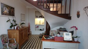 A room with a checkered floor, a wooden desk with a computer, a chair, and a staircase. - Le Logis de la Lande (La Boissiere-des-Landes)