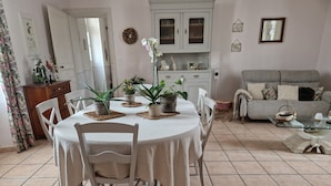 A dining area with a round table, white chairs, and potted plants. - Le Logis de la Lande (La Boissiere-des-Landes)