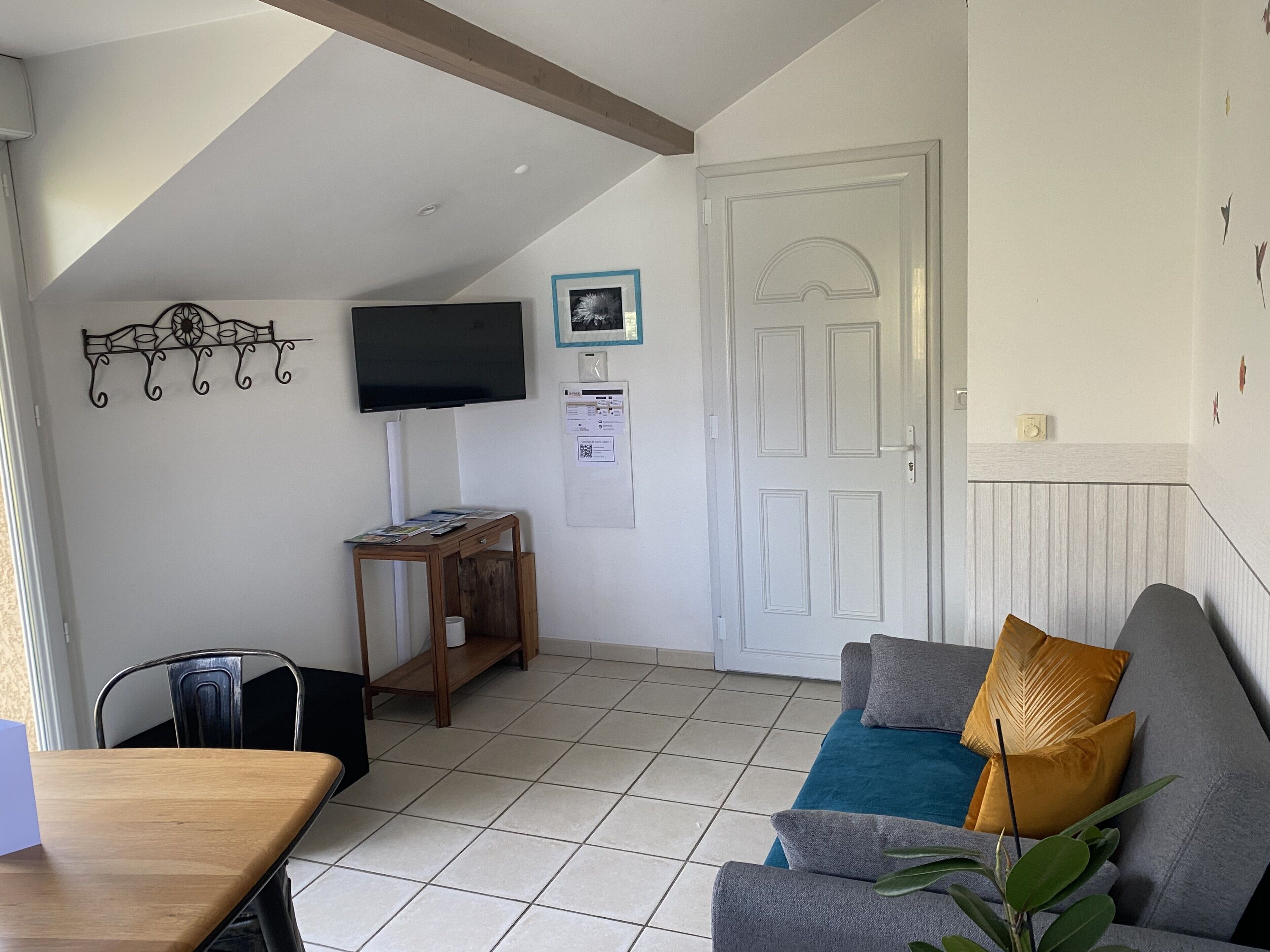 Een woonkamer met een bank, een salontafel, een aan de muur bevestigde televisie en een deur.