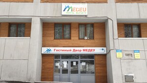 A hotel entrance with a sign reading "Gostinyy Dvor MEDEU HOTEL ALMATY".