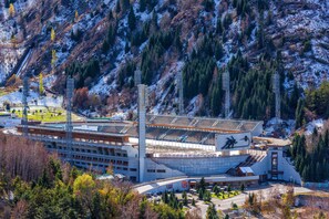 Ein großes Stadion mit mehreren Sitzreihen, umgeben von Bergen und Bäumen.