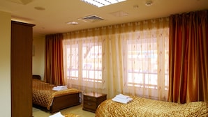 A hotel room with two beds, a nightstand, and a window with curtains.