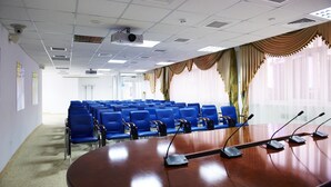 A conference room with a large oval table, blue chairs, and microphones.