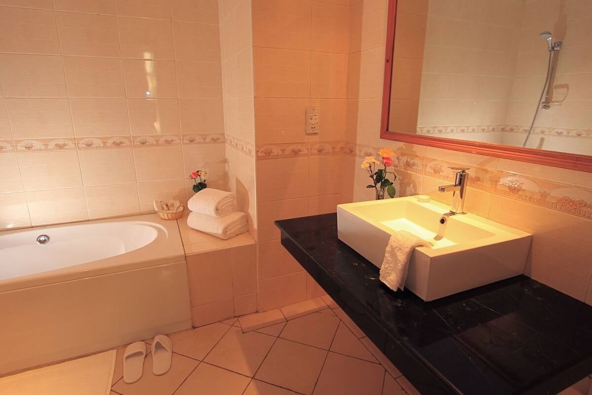A bathroom with a bathtub, a sink, and a mirror.
