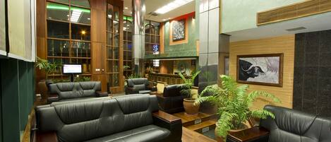 A lobby with leather sofas, a reception desk, and a large window.