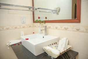 Un baño con lavamanos blanco, un espejo y un perchero para toallas.