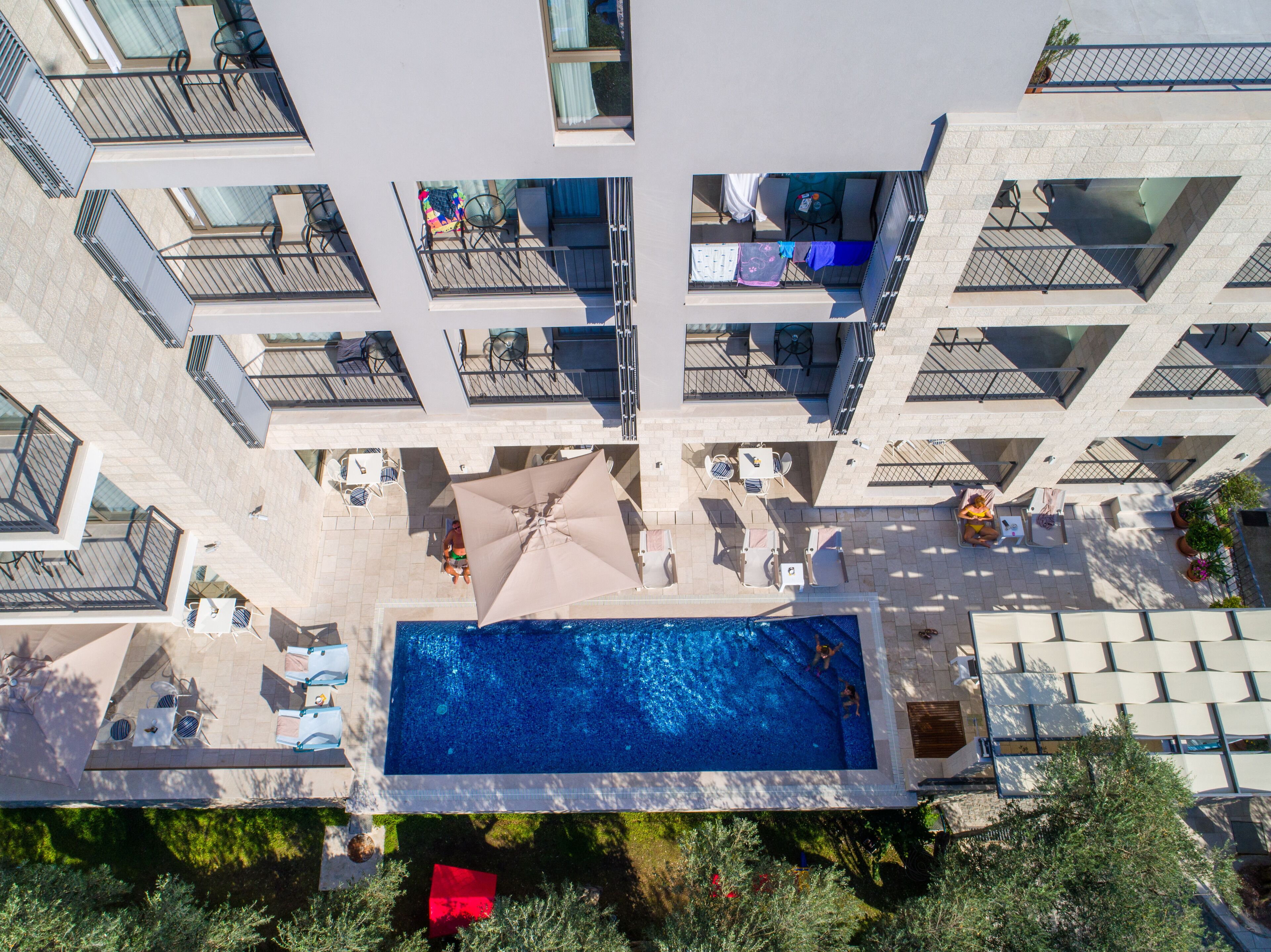 A high-rise hotel with a central swimming pool surrounded by outdoor seating and sun loungers.