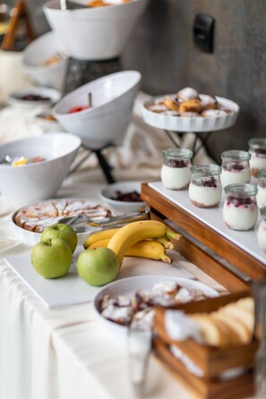 A buffet table with various food items including fruits, desserts, and small jars of food. - Hotel Eleven (Petrovac)