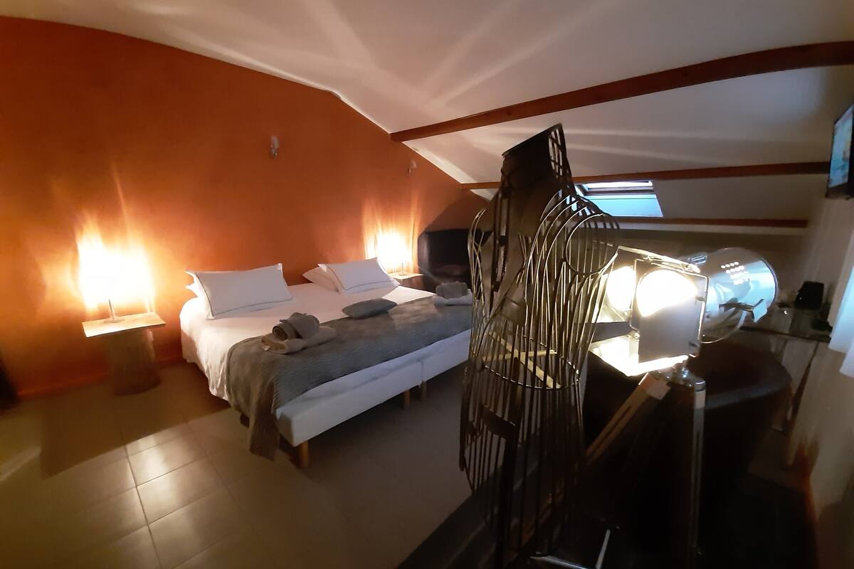 A hotel room with a bed, bedside lamps, a desk with a lamp, and a chair.