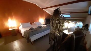 Una habitación de hotel con cama, lámparas de noche, escritorio con lámpara y una silla.