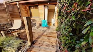 Una terraza de madera con zona de estar, una mesita y una silla.