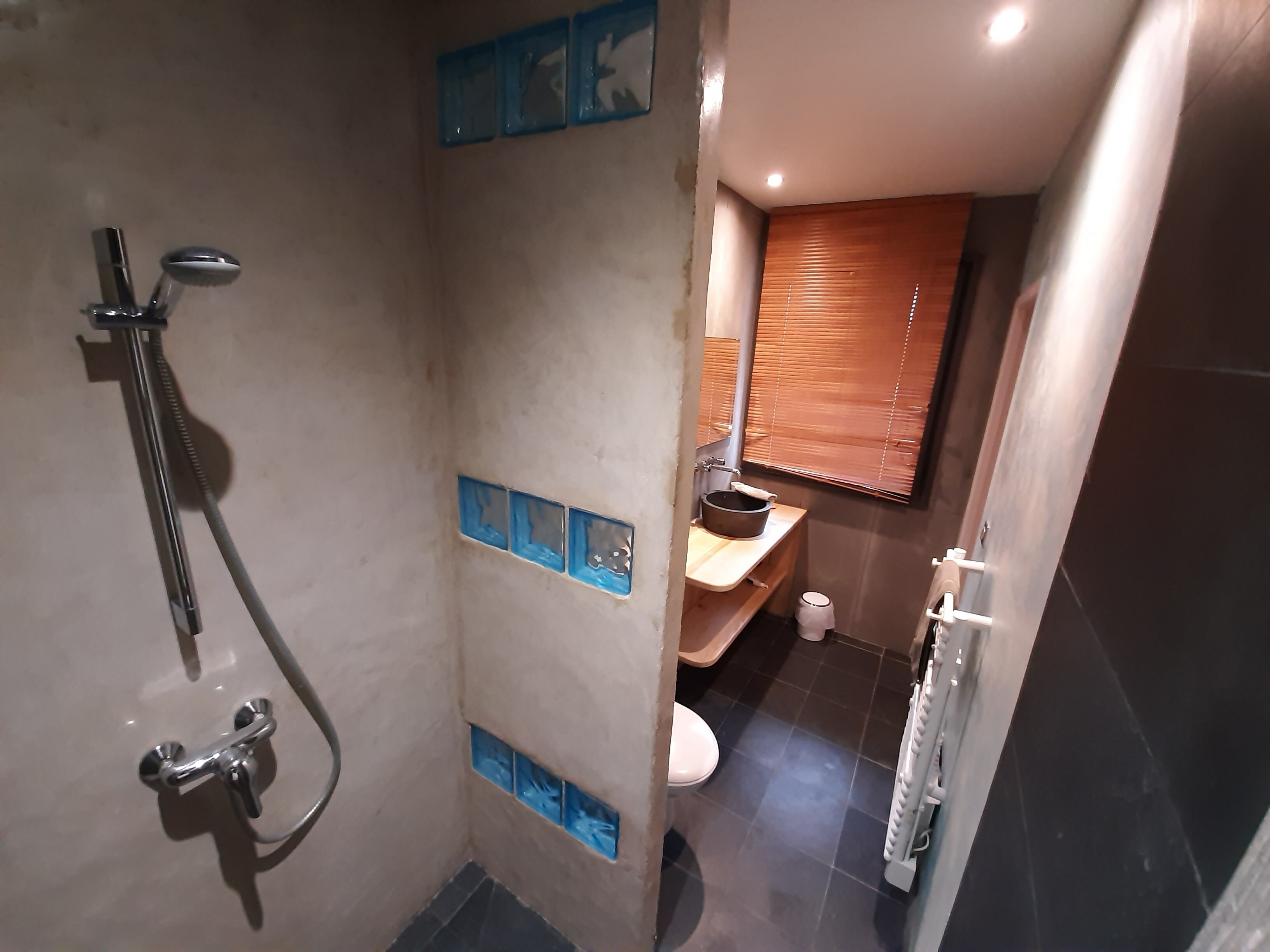Een badkamer met douche, toilet en wastafel.