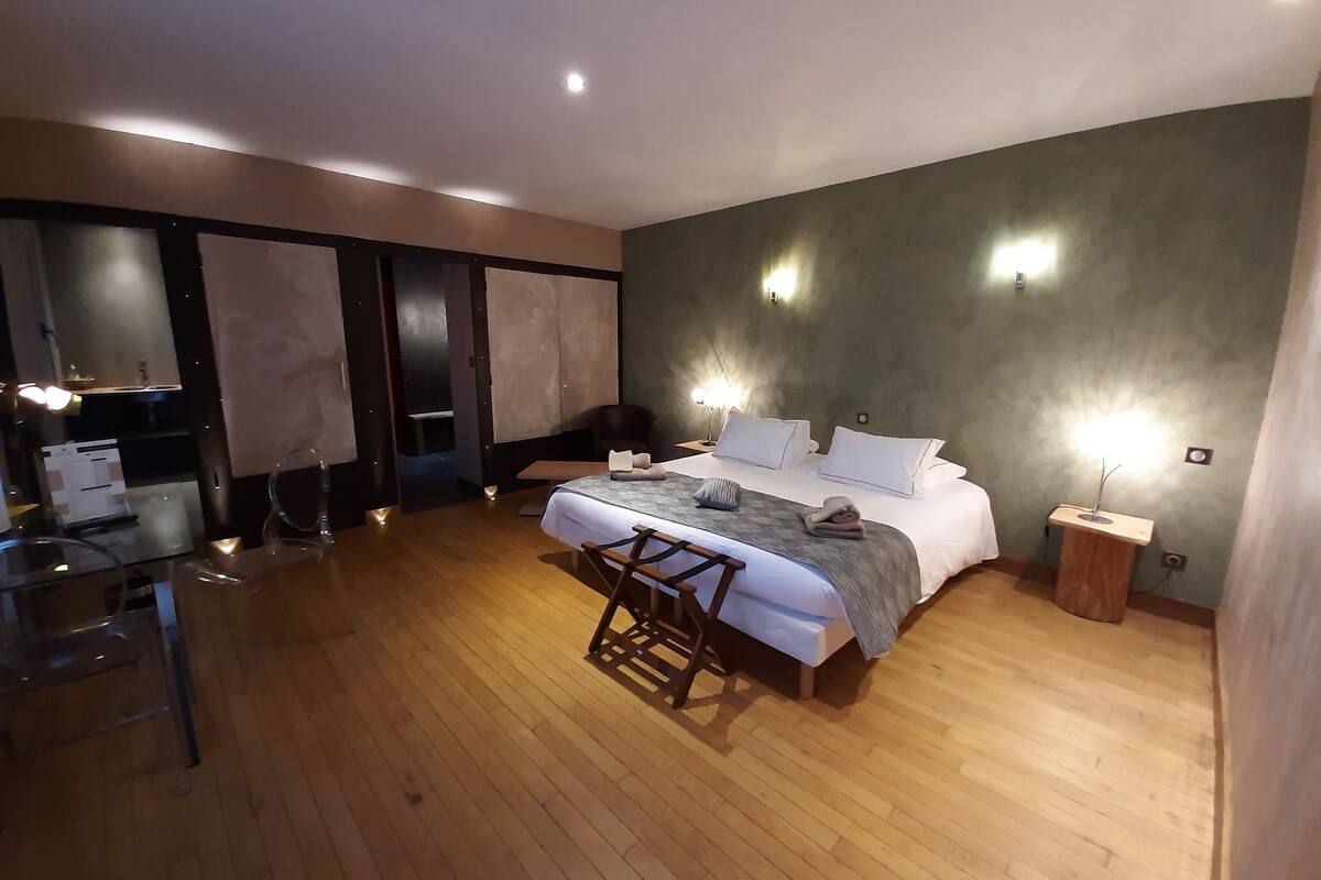 A modern hotel room with a large bed, a desk, and a chair.