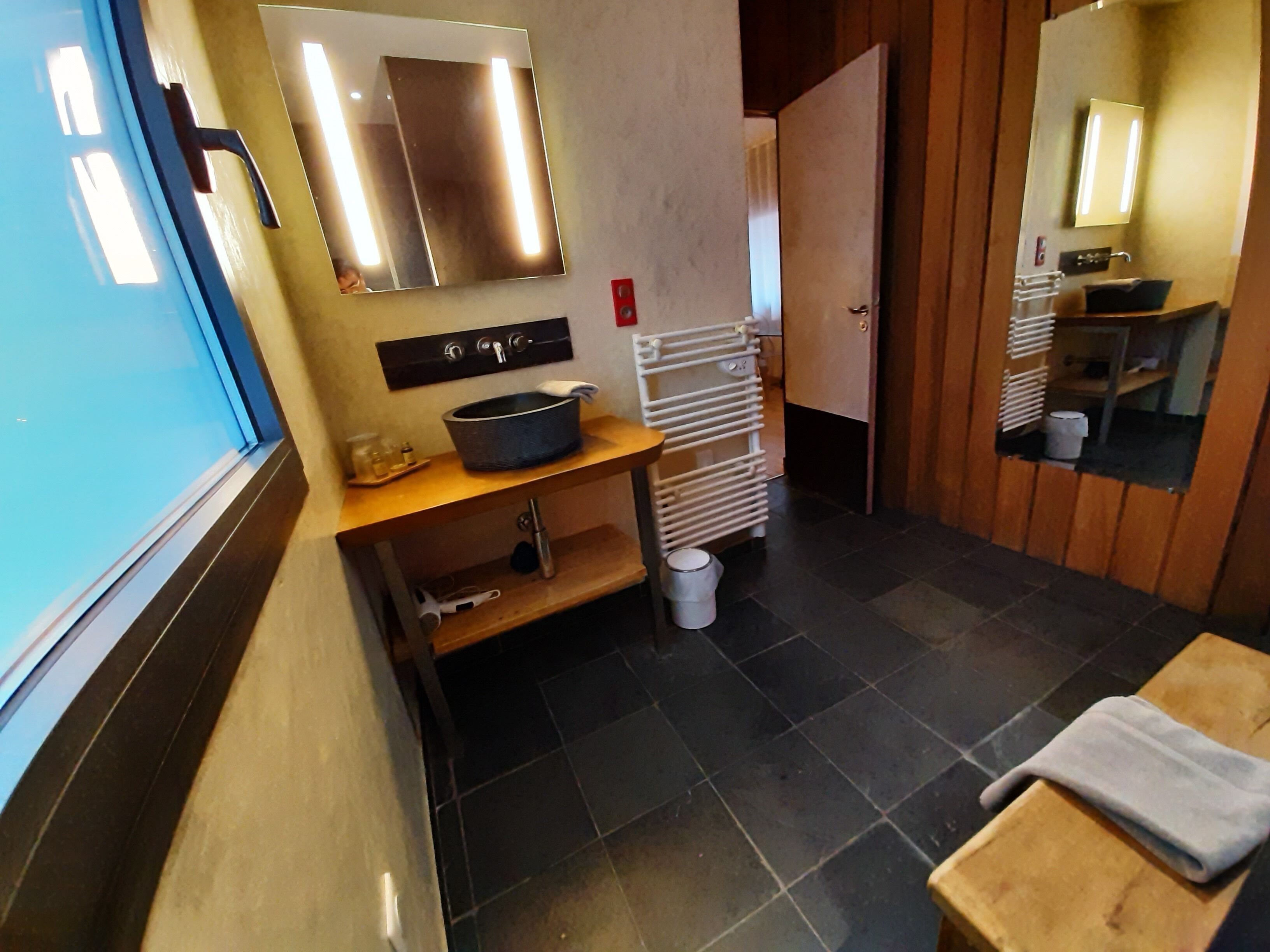 A bathroom with a sink, mirror, towel rack, and a small table with a towel.