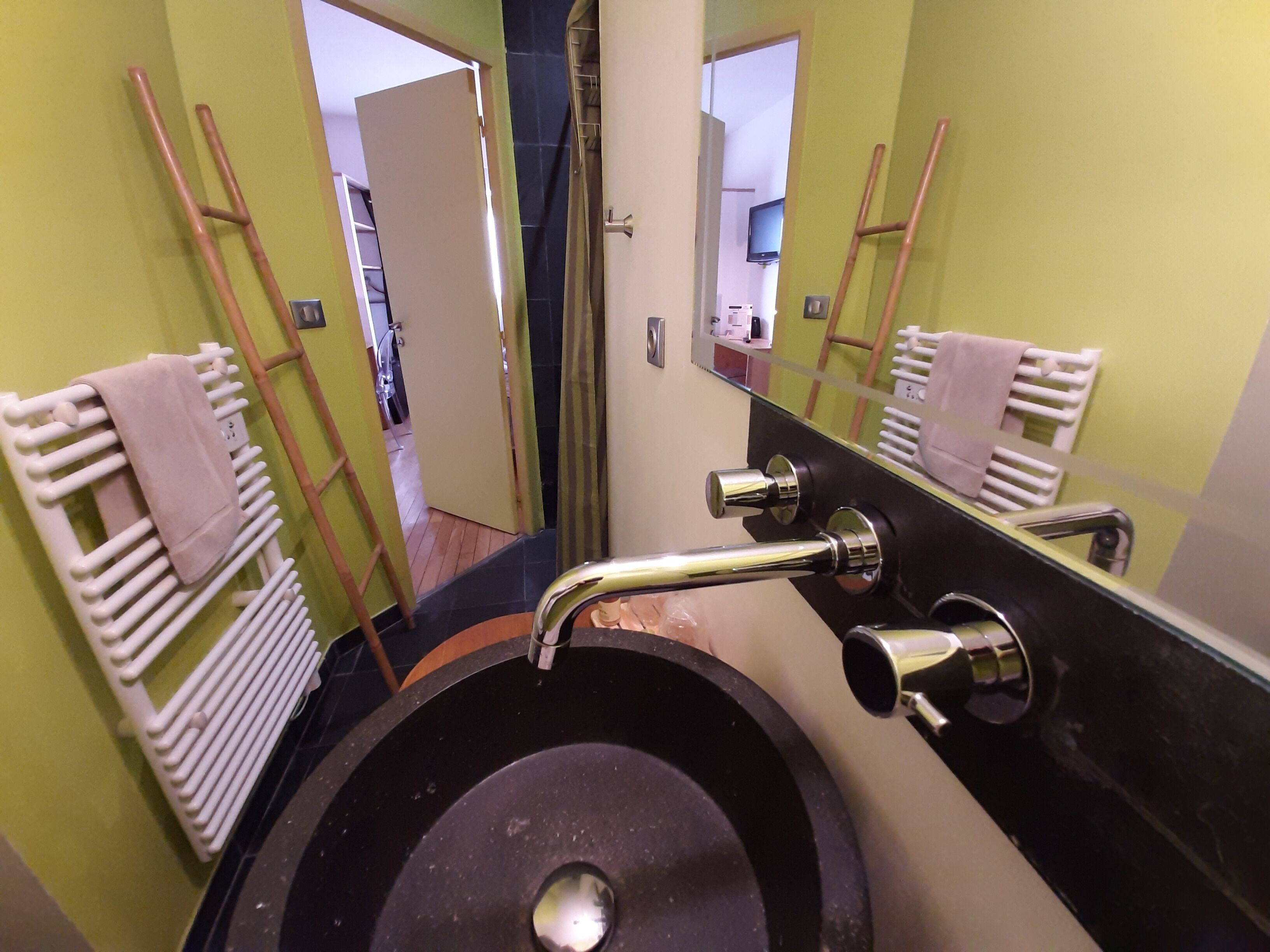 A bathroom with a black sink, a mirror, and a towel rack.