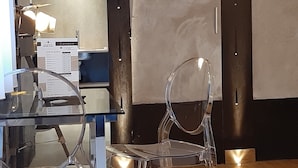 Una habitación con una mesa de vidrio, una silla transparente y un escritorio con una computadora y documentos.