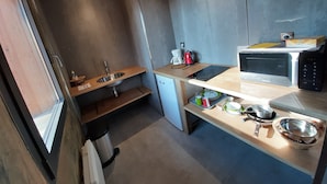 Una cocina compacta con un lavamanos, un microondas y una pequeña encimera.