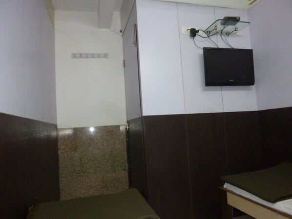 A hotel room with a bed, a television mounted on the wall, and a small table.