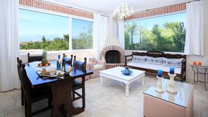 A dining area with a table set for two, a sofa, and a fireplace. - Villa Dafni (Faistos)