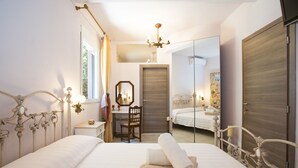 A bedroom with a large bed, a desk, a chair, a mirror, and a wardrobe. - Villa Dafni (Faistos)