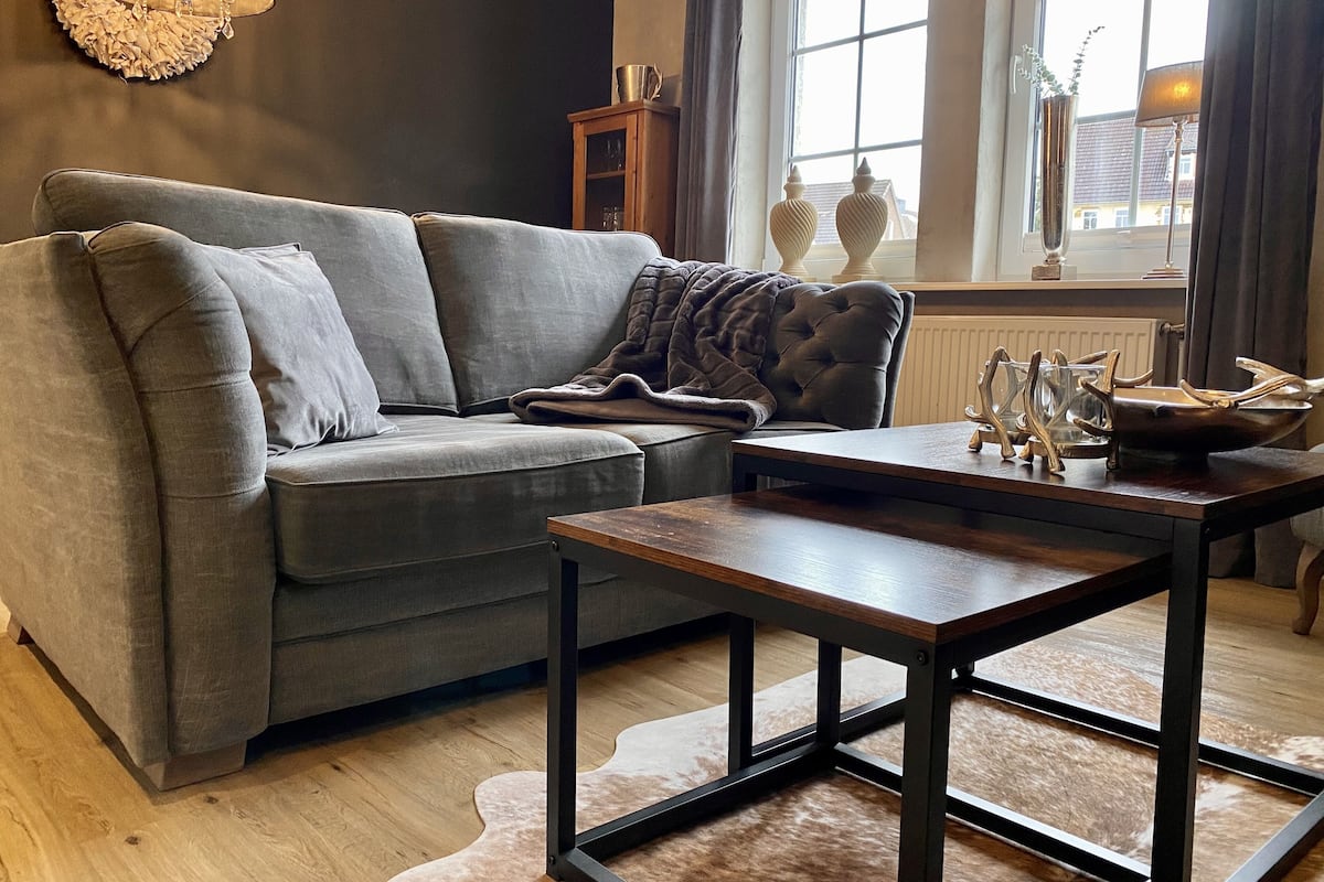 A modern living room with a grey sofa, a wooden coffee table, and a fur rug.