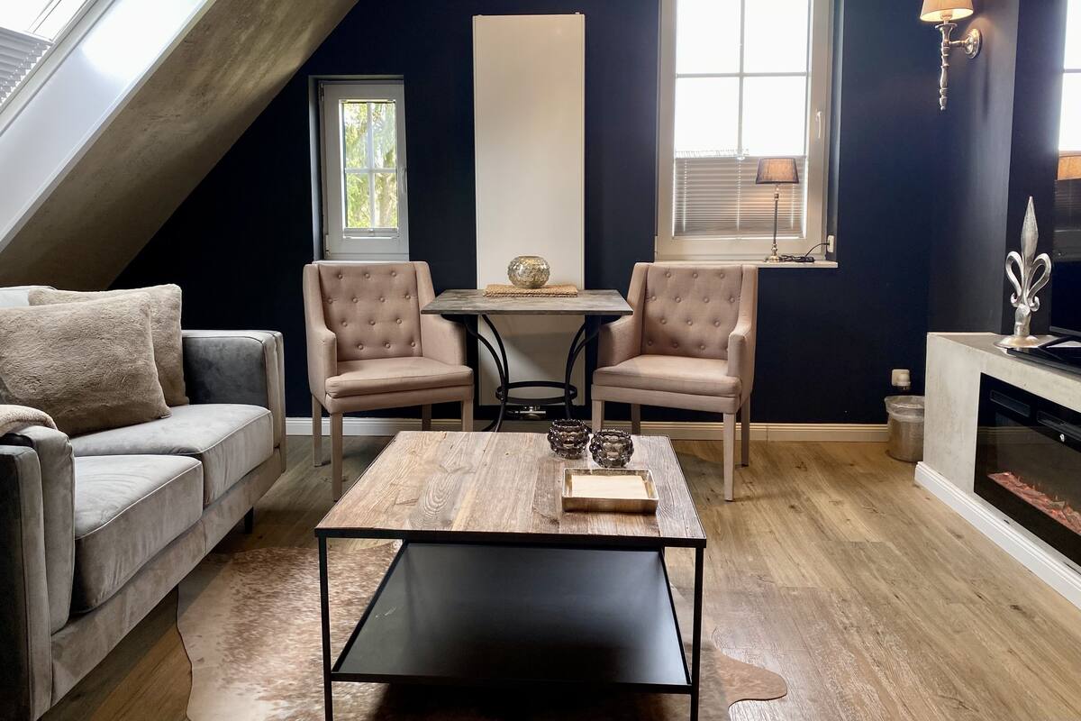 A cozy living room with a sofa, two armchairs, a coffee table, and a fireplace.