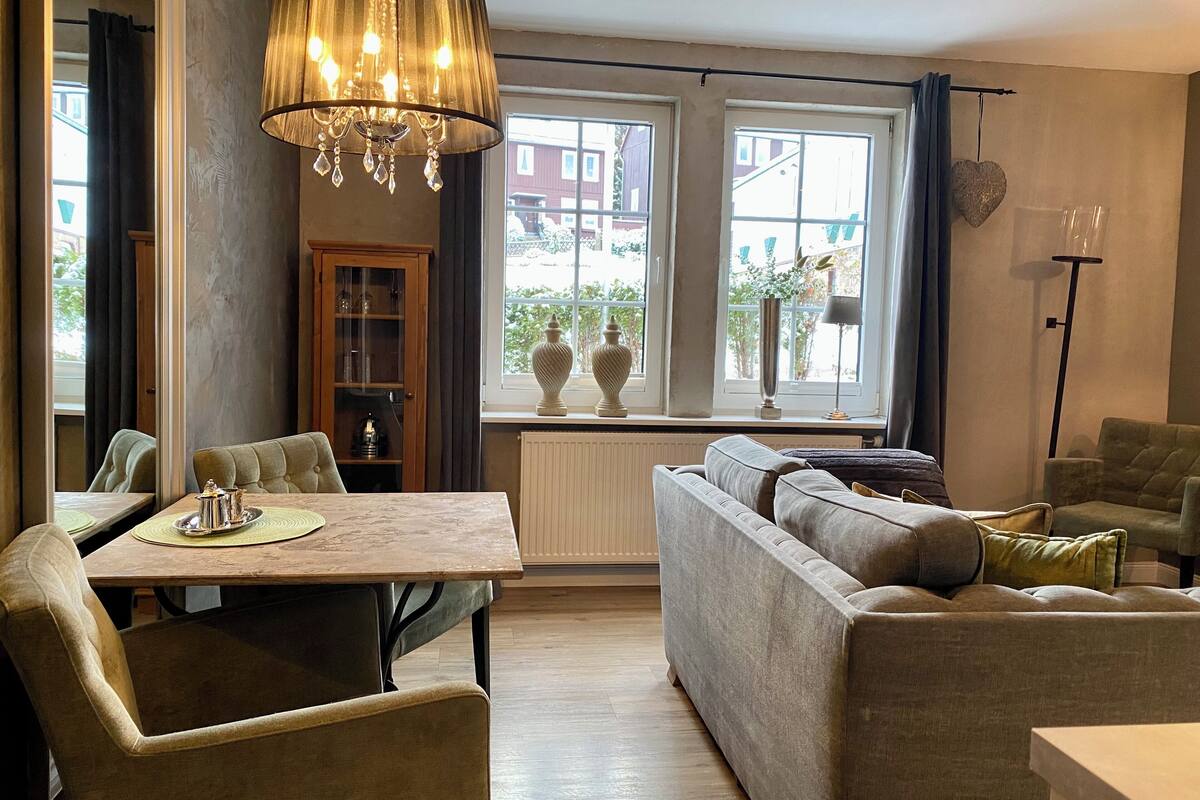 A cozy living room with a dining table, sofa, and a chandelier.